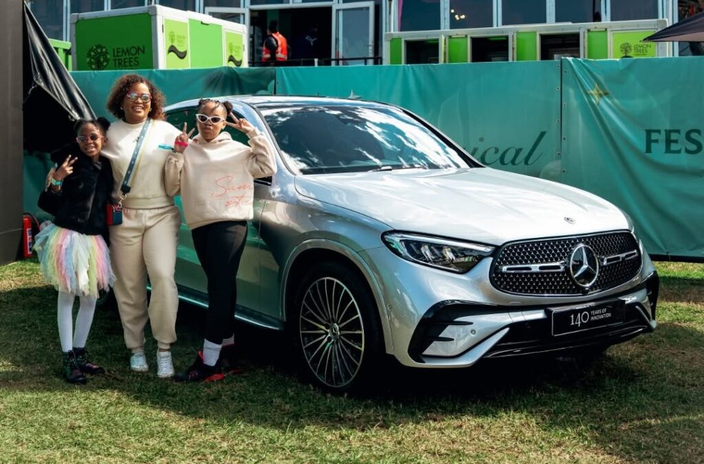 A family posing proudly next to a silver Mercedes-Benz GLC Coupe at an outdoor event, representing the premium lifestyle appeal of this luxury SUV