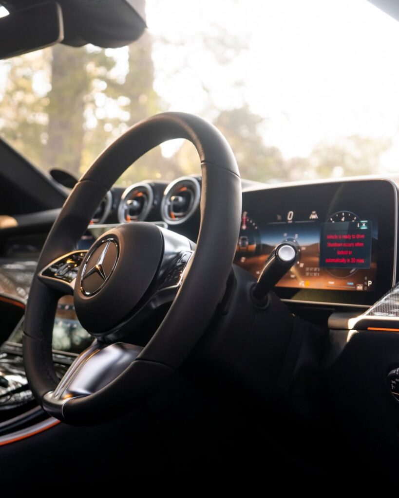 Alt Text: Close-up of the multi-function leather steering wheel and digital instrument cluster inside the Mercedes-Benz GLC Coupe, highlighting its advanced cabin technology